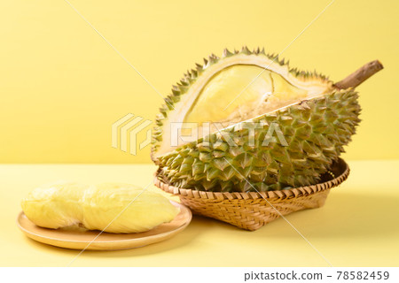 Ripe Thai durian fruit (Monthong) in a basket and plate on yellow background, Tropical fruit 78582459