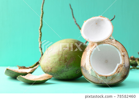 Peeled young coconut fruit on green color background, Summer tropical fruit 78582460