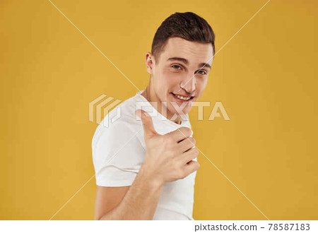 handsome man in white t-shirt gesturing with his hands yellow background 78587183