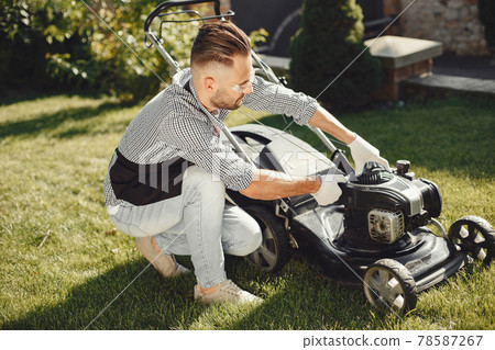 Man repairs lawnmover in a backyard 78587267