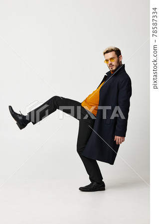 guy in coat lifted his leg up orange sweater suit model guy in coat lifted his leg up orange sweater suit model 78587334