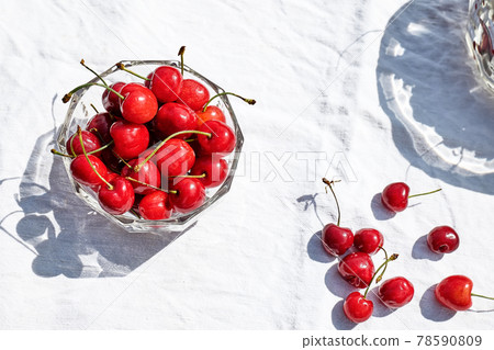 Fresh healthy ripe cherries in glass bowl on table with white tablecloth. Summer sweet seasonal organic fruits. Top view. Selective focus 78590809