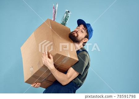 A man in working uniform with boxes in the hands of a carriage delivery service blue background 78591798