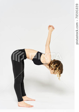 sporty woman in black jeans and a t-shirt doing exercises in a bright room sporty woman in black jeans and a t-shirt doing exercises in a bright room 78591839