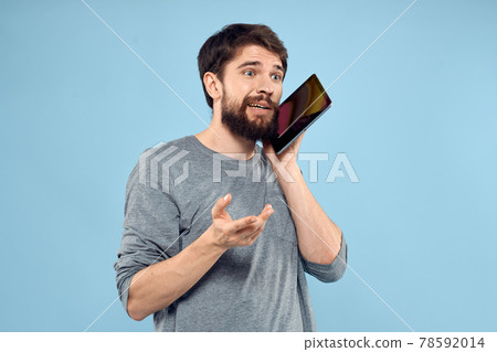 Emotional man with a tablet in the hands of a wireless device internet technology lifestyle blue background Emotional man with a tablet in the hands of a wireless device internet technology lifestyle blue background 78592014