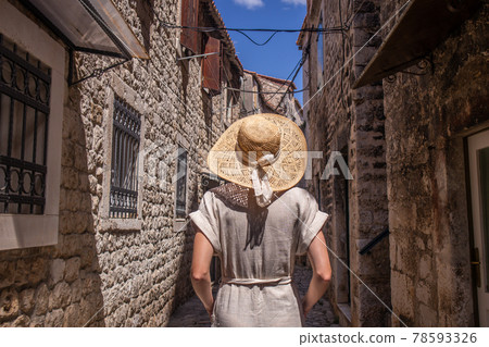 Beautiful blonde young female traveler wearing straw sun hat sightseeing and enjoying summer vacation in an old traditional costal town at Adriatic cost, Croatia 78593326