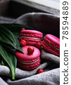 vibrant pink macaroon cakes side view with berries and green leaves on gray fabric background closeup. Selective focus 78594889
