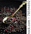 multicolored pepper corns in golden metal spoon side view on dark blurred background closeup. Selective focus 78594892