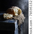 loaf of wheat homemade bread on wooden table side view on a dark background with steam closeup. Selective focus 78595152