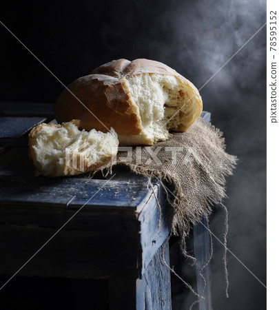 loaf of wheat homemade bread on wooden table side view on a dark background with steam closeup. Selective focus 78595152