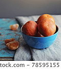 fresh delicious tangerines in blue bowl side view on gray towel on blue rustic background closeup. Selective focus 78595155