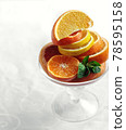 fresh citrus oranges and lemons sliced in glass vase with mint side view on white background closeup. Selective focus 78595158