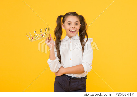 That pride of hers. Happy small girl holding crown with pride on yellow background. Adorable little school beauty queen smiling and feeling great pride. Its a matter of her pride That pride of hers. Happy small girl holding crown with pride on yellow background. Adorable little school beauty queen smiling and feeling great pride. Its a matter of her pride 78595417