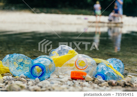 PLASTIC POLLUTION in the river. Dirty plastic bottles and bags on a garbage. River pollution, plastic in water. Pollution and recycle eco concept. 78595451