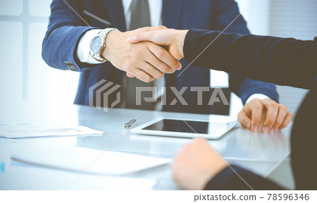 Businesspeople or lawyers shaking hands finishing up a meeting in blue toned office , close-up. Success at negotiation and handshake concepts 78596346