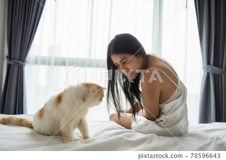 Asaian woman look and play cat on bed in morning 78596643
