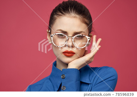 Portrait of a woman in glasses and in a blue shirt red lips pink background model Portrait of a woman in glasses and in a blue shirt red lips pink background model 78596839