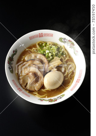 A bird's-eye view of hot pork bone soy sauce ramen with roasted char siu, taste balls, menma and all-purpose green onions on a black background 78597450