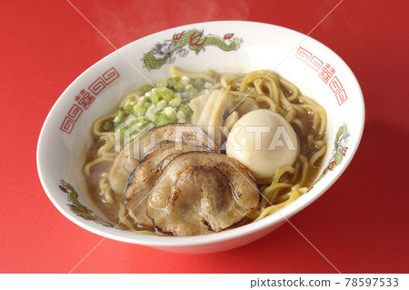 Photographed hot pork bone soy sauce ramen with roasted char siu, taste balls, menma and all-purpose green onions on a red background 78597533