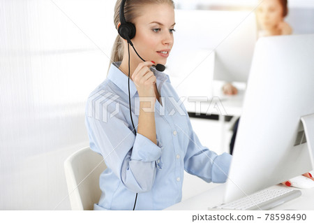 Blond woman working in sunny call center. Group of diverse people working as customer service occupation. Business concept Blond woman working in sunny call center. Group of diverse people working as customer service occupation. Business concept 78598490
