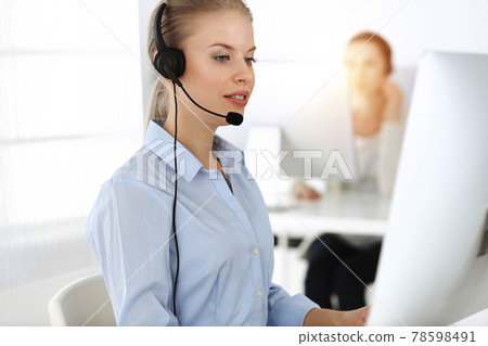 Blond woman working in sunny call center. Group of diverse people working as customer service occupation. Business concept Blond woman working in sunny call center. Group of diverse people working as customer service occupation. Business concept 78598491
