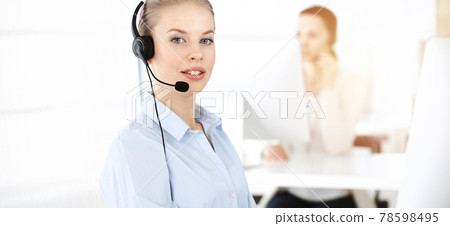 Blond woman working in sunny call center. Group of diverse people working as customer service occupation. Business concept 78598495