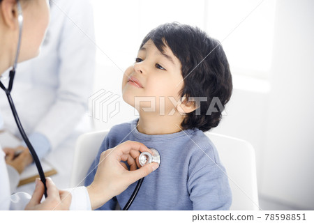 Doctor-woman examining a child patient by stethoscope. Cute arab boy at physician appointment. Medicine concept Doctor-woman examining a child patient by stethoscope. Cute arab boy at physician appointment. Medicine concept 78598851
