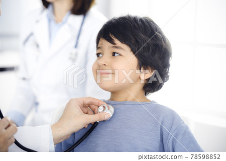 Doctor-woman examining a child patient by stethoscope. Cute arab boy at physician appointment. Medicine concept Doctor-woman examining a child patient by stethoscope. Cute arab boy at physician appointment. Medicine concept 78598852