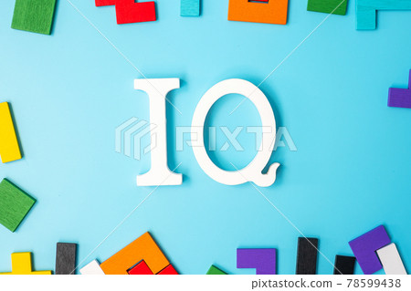 IQ text with colorful wood puzzle pieces, geometric shape block on blue background. Concept of intelligence quotient and logic thinking 78599438