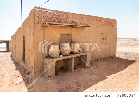 House built of mud bricks in the desert with a bench on which drinking clay jugs with water are standing ready. House built of mud bricks in the desert with a bench on which drinking clay jugs with water are standing ready. 78600084