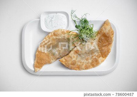 cheburek or fried dough pie with meat feeling and sauce on white background cheburek or fried dough pie with meat feeling and sauce on white background 78600487