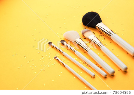 Makeup brushes in different sizes on a yellow background and glitter cropped look Makeup brushes in different sizes on a yellow background and glitter cropped look 78604596