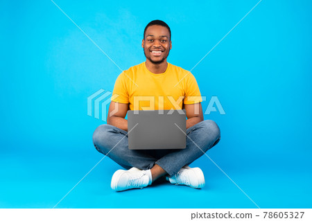 Happy African American Guy Sitting With Laptop Over Blue Background Happy African American Guy Sitting With Laptop Over Blue Background 78605327