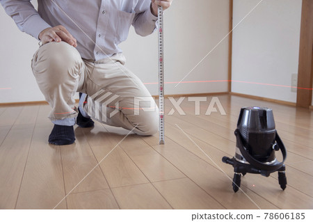 Workers measuring floor height with a laser marking device 78606185