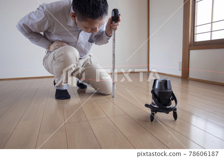 Workers measuring floor height with a laser marking device Workers measuring floor height with a laser marking device 78606187