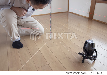 Workers measuring floor height with a laser marking device Workers measuring floor height with a laser marking device 78606188