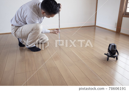 Workers measuring floor height with a laser marking device 78606191