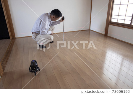 Workers measuring floor height with a laser marking device Workers measuring floor height with a laser marking device 78606193