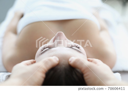 Young woman masseur makes face and head massage in spa salon 78606411