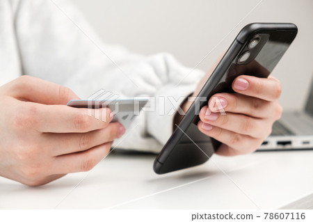Close up woman hand holding credit card and smartphone for making purchase in online shop 78607116