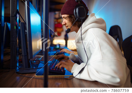 Young gamer in headset play shooter in game club Young gamer in headset play shooter in game club 78607759