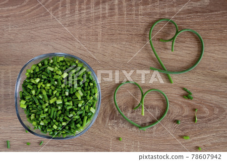 Heart shaped green garlic arrows on wooden background Heart shaped green garlic arrows on wooden background 78607942