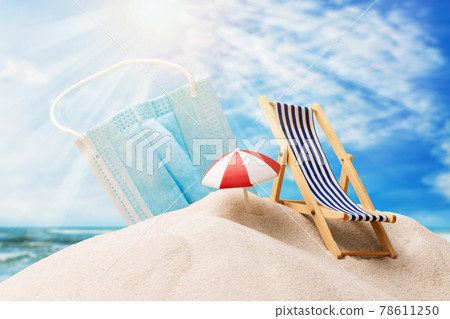 Medical mask in the sand and toy beach accessories against the backdrop of the seascape, concept on the topic of wearing personal protective equipment on the beach 78611250