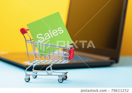 Paper sticker with text in toy grocery cart on laptop background, online sale concept Paper sticker with text in toy grocery cart on laptop background, online sale concept 78611252