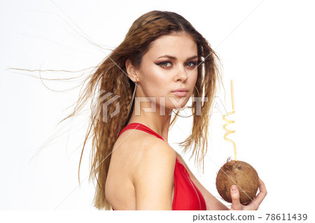 woman drinks coconut cocktail through a straw lifestyle red t-shirt light background 78611439