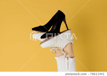 Female feet in sneakers black fashion shoes yellow background 78611441