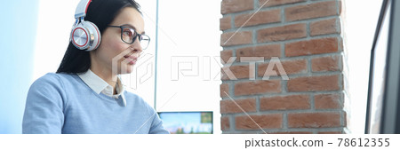 Young woman in headphones working at computer Young woman in headphones working at computer 78612355