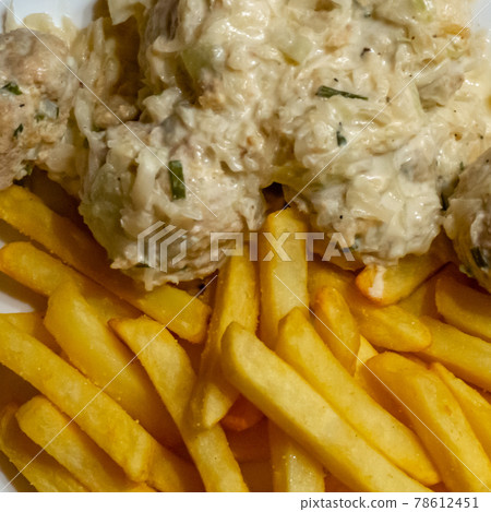 Polish meatballs in cream sauce with celery and spring onions on french fries made from fresh potatoes, homemade fare 78612451
