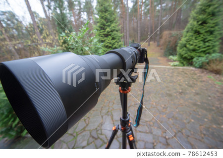 Long black zoom lens with focal length 150 mm to 600 mm on a mirrorless camera on a tripod 78612453