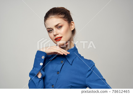 An elegant lady in a blue shirt is gesturing with her hands on a light background and a copy space close-up portrait An elegant lady in a blue shirt is gesturing with her hands on a light background and a copy space close-up portrait 78612465